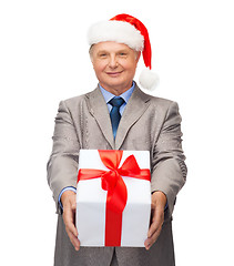 Image showing smiling man in suit and santa helper hat with gift