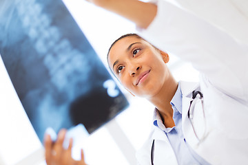 Image showing smiling female doctor studying x-ray