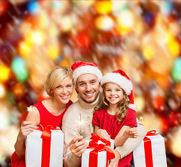 Image showing smiling family holding gift boxes and sparkles