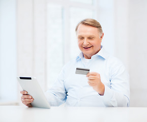 Image showing old man with tablet pc and credit card at home