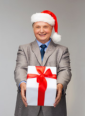 Image showing smiling man in suit and santa helper hat with gift