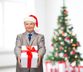 Image showing smiling man in suit and santa helper hat with gift