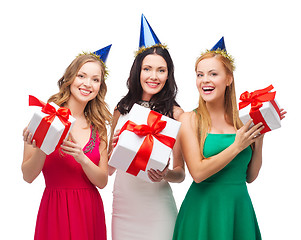 Image showing three smiling women in blue hats with gift boxes