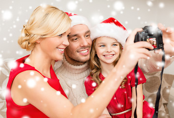 Image showing smiling family in santa helper hats taking picture