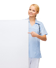 Image showing smiling female doctor or nurse with blank board