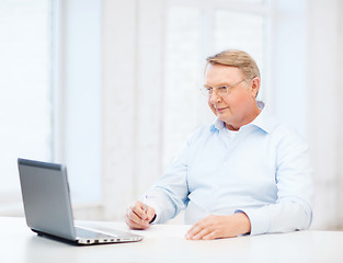 Image showing old man in eyeglasses filling a form at home