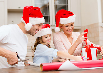 Image showing smiling family in santa helper hats with gift box