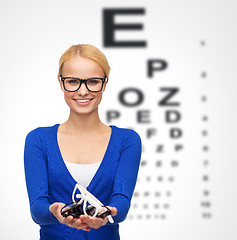 Image showing smiling woman wearing and holding eyeglasses