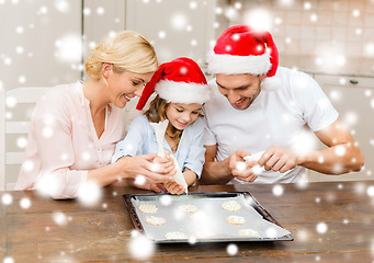 Image showing happy family in santa helper hats making cookies