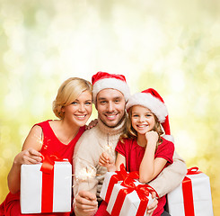 Image showing smiling family holding gift boxes and sparkles