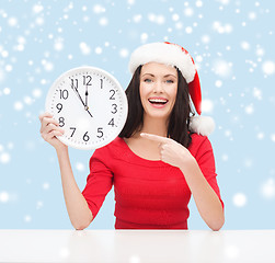 Image showing woman in santa helper hat with clock showing 12