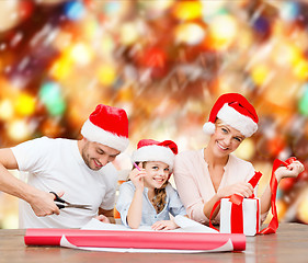 Image showing smiling family in santa helper hats with gift box