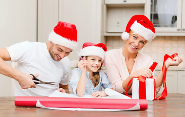 Image showing smiling family in santa helper hats with gift box