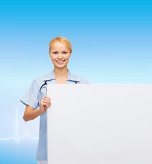 Image showing smiling female doctor or nurse with blank board