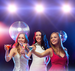 Image showing three smiling women with cocktails and disco ball