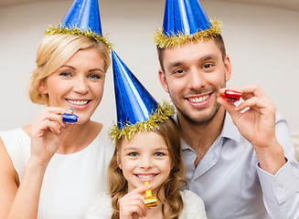 Image showing smiling family in blue hats blowing favor horns