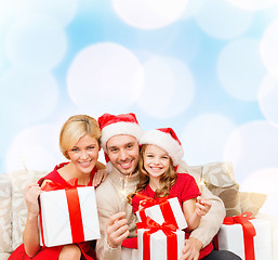 Image showing smiling family holding gift boxes and sparkles