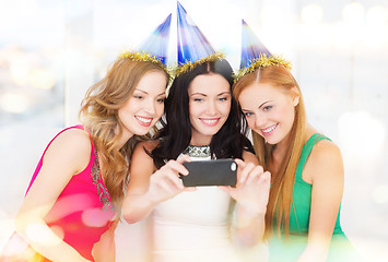 Image showing three smiling women in hats having fun with camera