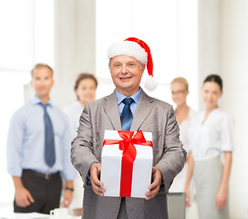 Image showing smiling man in suit and santa helper hat with gift