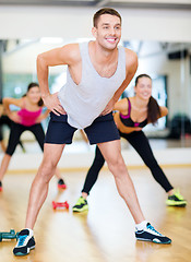 Image showing smiling male trainer working out in the gym