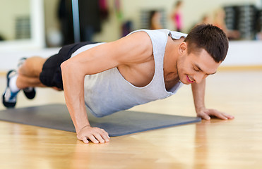 Image showing smiling man doing push-ups in the gym