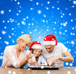 Image showing happy family in santa helper hats making cookies