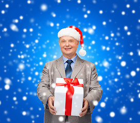 Image showing smiling man in suit and santa helper hat with gift