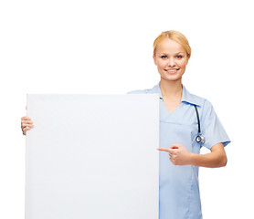 Image showing smiling female doctor or nurse with blank board