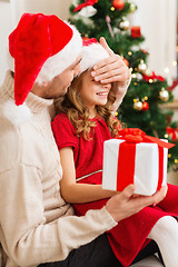 Image showing smiling father surprises daughter with gift box