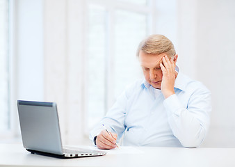 Image showing old man filling a form at home