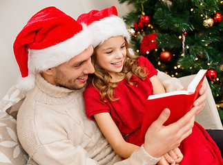 Image showing smiling father and daughter reading book