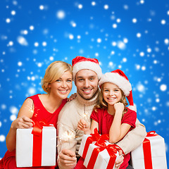 Image showing smiling family holding gift boxes and sparkles