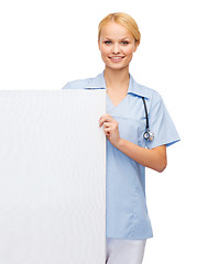 Image showing smiling female doctor or nurse with blank board