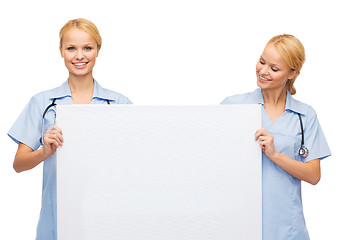 Image showing smiling female doctor or nurse with blank board