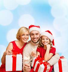 Image showing smiling family holding gift boxes and sparkles