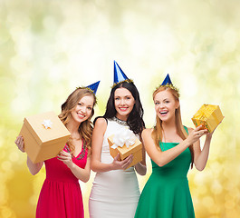 Image showing three smiling women in blue hats with gift boxes