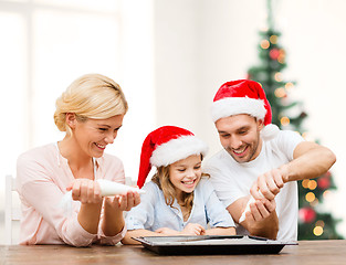 Image showing happy family in santa helper hats making cookies