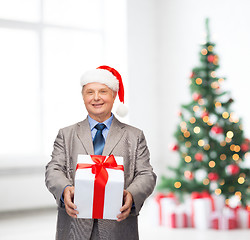 Image showing smiling man in suit and santa helper hat with gift