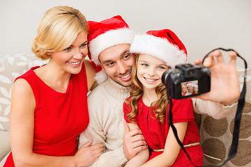 Image showing smiling family in santa helper hats taking picture