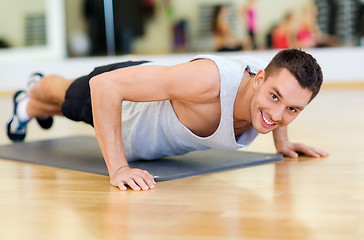 Image showing smiling man doing push-ups in the gym