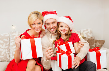 Image showing smiling family holding gift boxes and sparkles