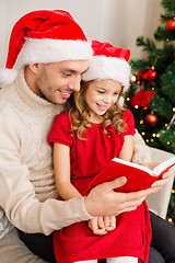 Image showing smiling father and daughter reading book