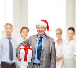 Image showing smiling man in suit and santa helper hat with gift