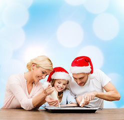 Image showing happy family in santa helper hats making cookies