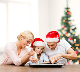 Image showing happy family in santa helper hats making cookies