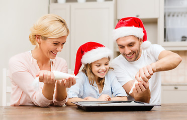 Image showing happy family in santa helper hats making cookies