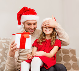 Image showing smiling father surprises daughter with gift box