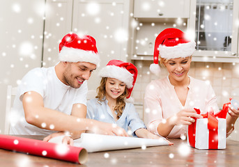 Image showing smiling family in santa helper hats with gift box