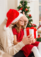 Image showing smiling father surprises daughter with gift box