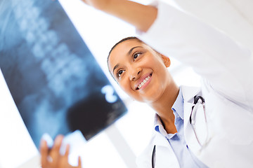 Image showing smiling female doctor studying x-ray